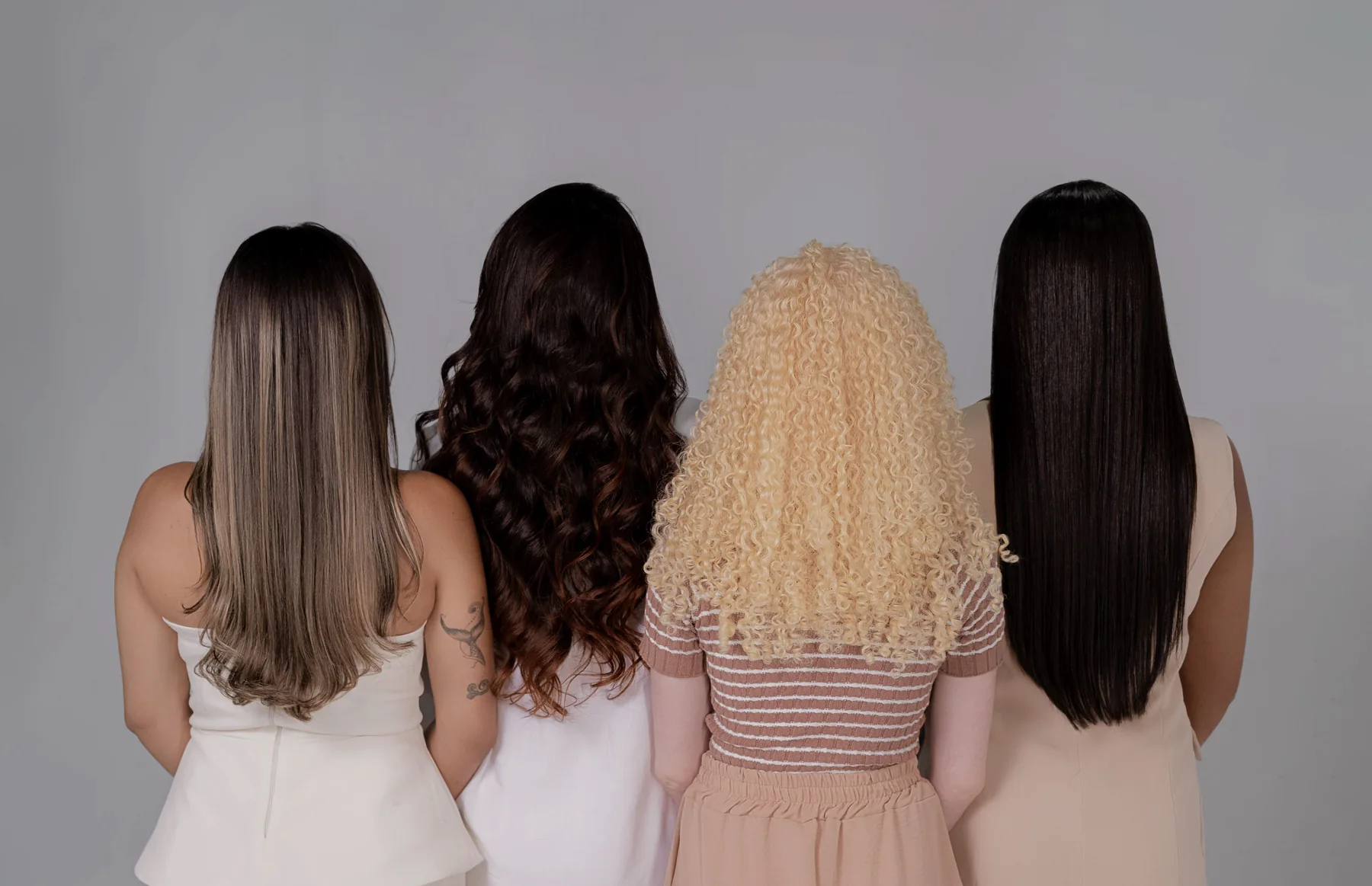 Four women viewed from behind showing straight, wavy and curly hair textures